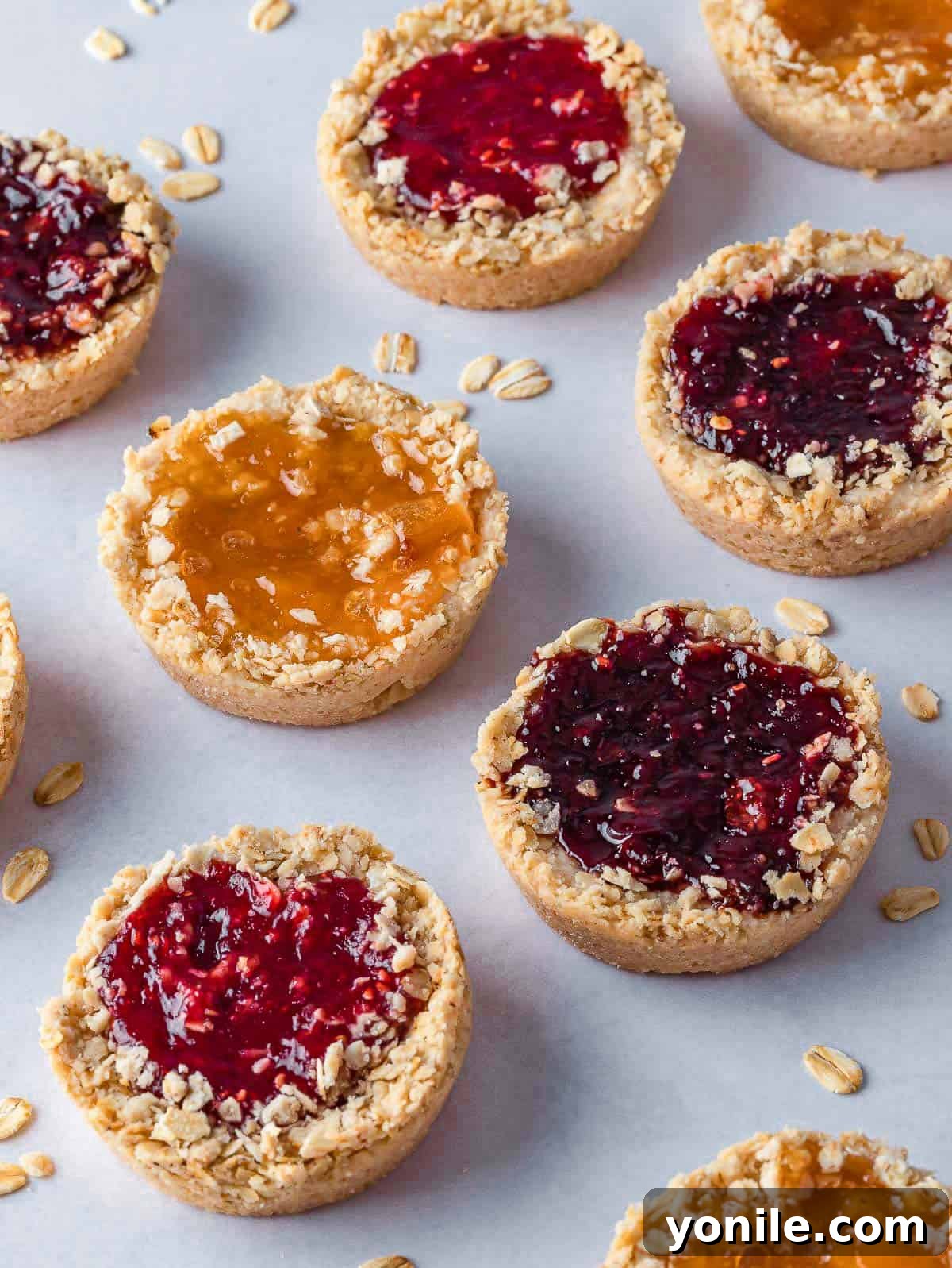 Chewy Oat Jam Treasures 2 Oatmeal cookies with jam on a tray, showcasing their vibrant filling and rustic texture.