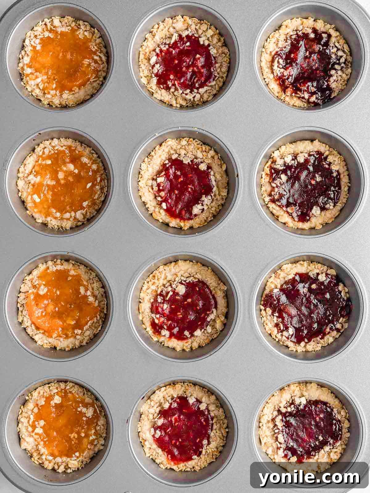 Chewy Oat Jam Treasures 6 Baked jam-filled cookies cooling in a muffin tin, golden brown and tempting.