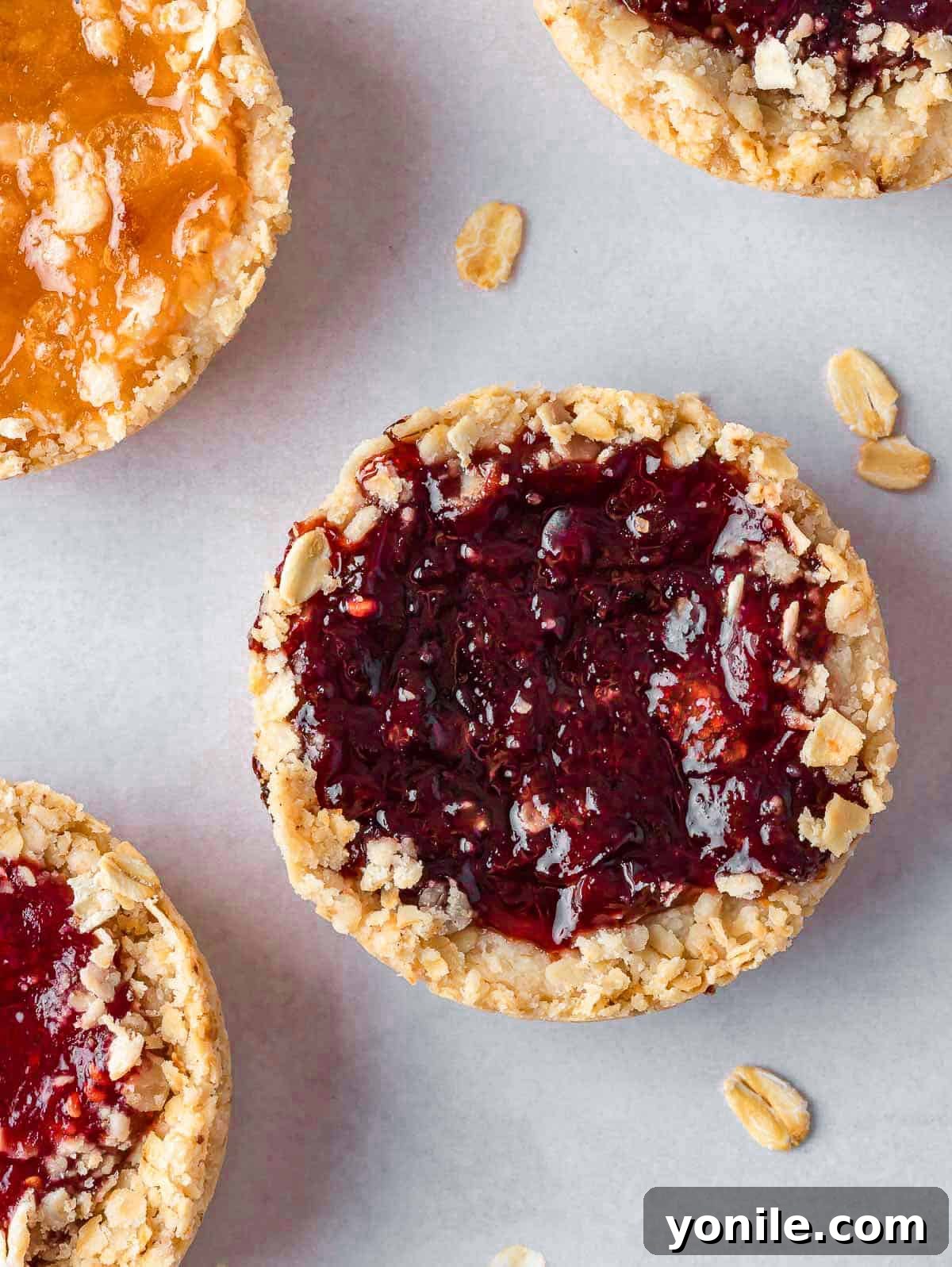 Chewy Oat Jam Treasures 8 Closeup of a single jam-filled oatmeal cookie, showing its golden edges and glistening fruit center.