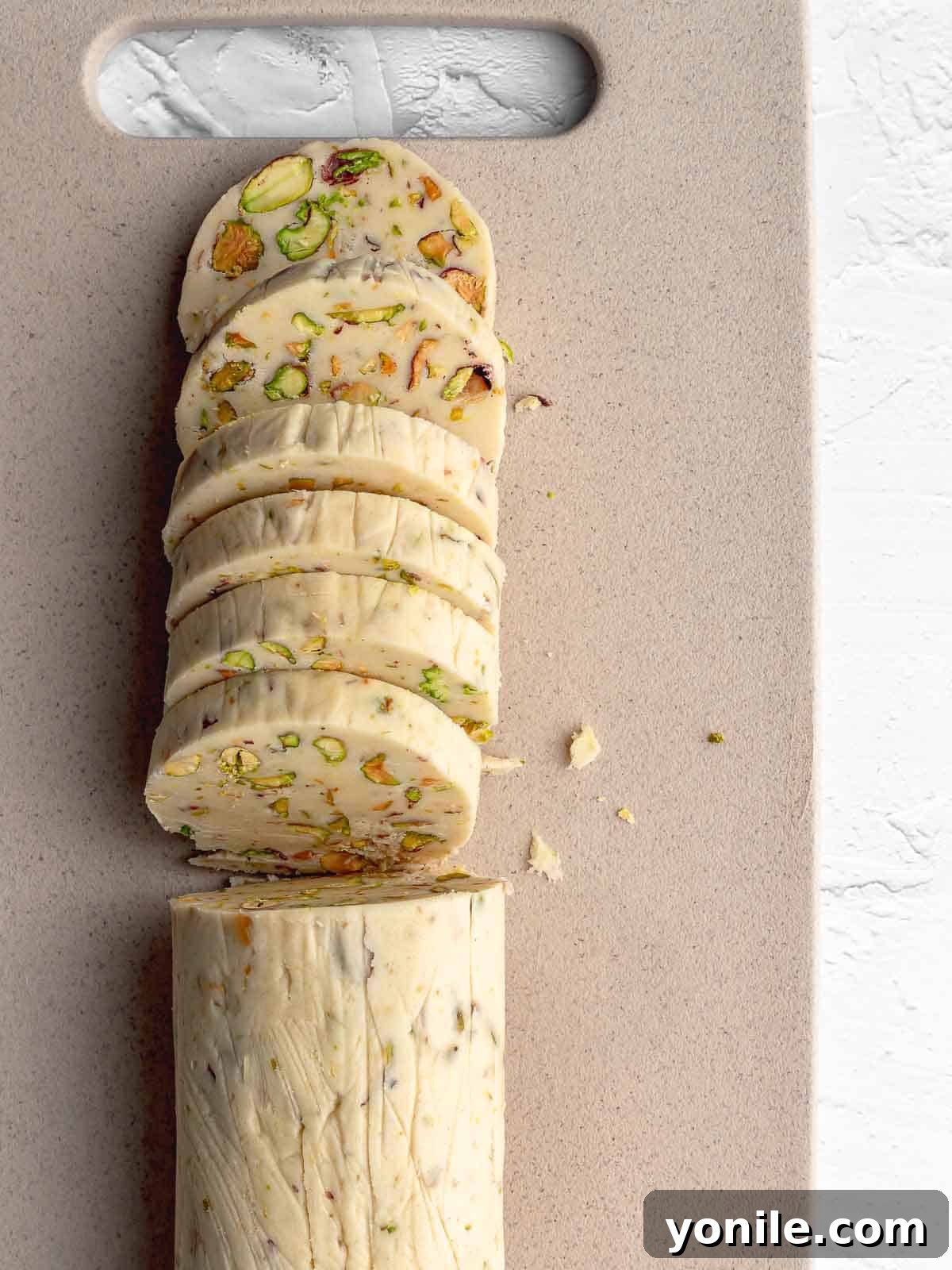 Buttery Pistachio Shortbread Delights 5 A perfectly formed log of pistachio shortbread cookie dough, neatly sliced into uniform rounds, ready for baking.