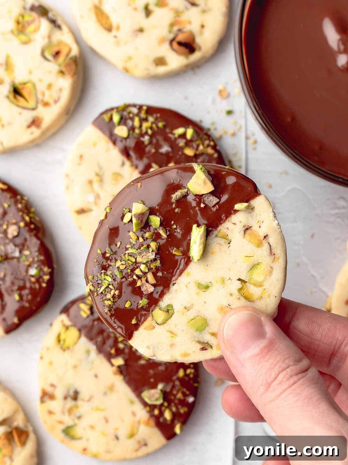 Buttery Pistachio Shortbread Delights 7 Finished shortbread cookies beautifully dipped in dark chocolate and sprinkled with extra pistachios, ready to enjoy.