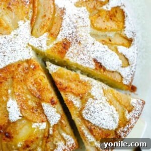 A piece of cake being taken out of the whole pear cake.