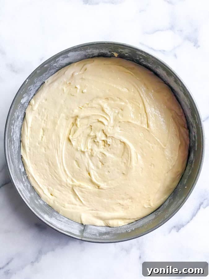 Moist pear cake batter neatly poured into a round baking pan, ready for pears.