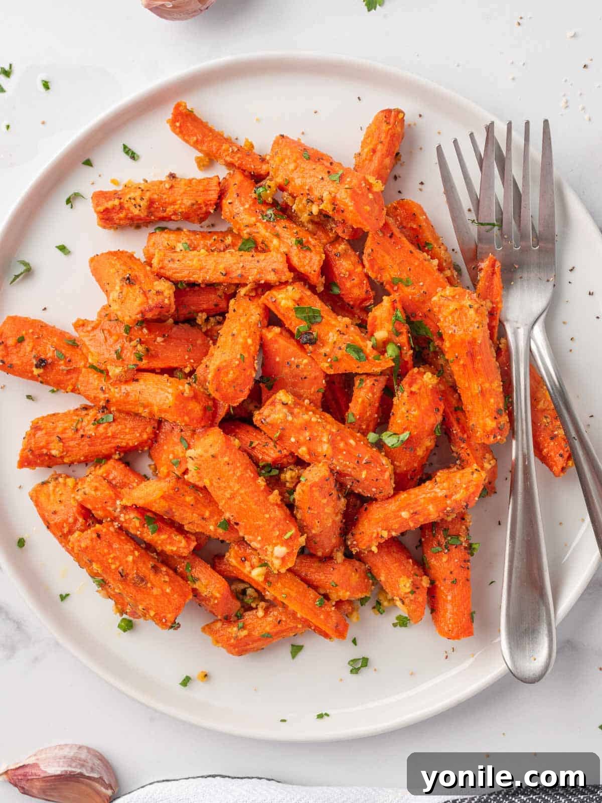 Roasted carrots with parmesan cheese on a plate with two forks, showcasing a perfectly golden and tender texture.