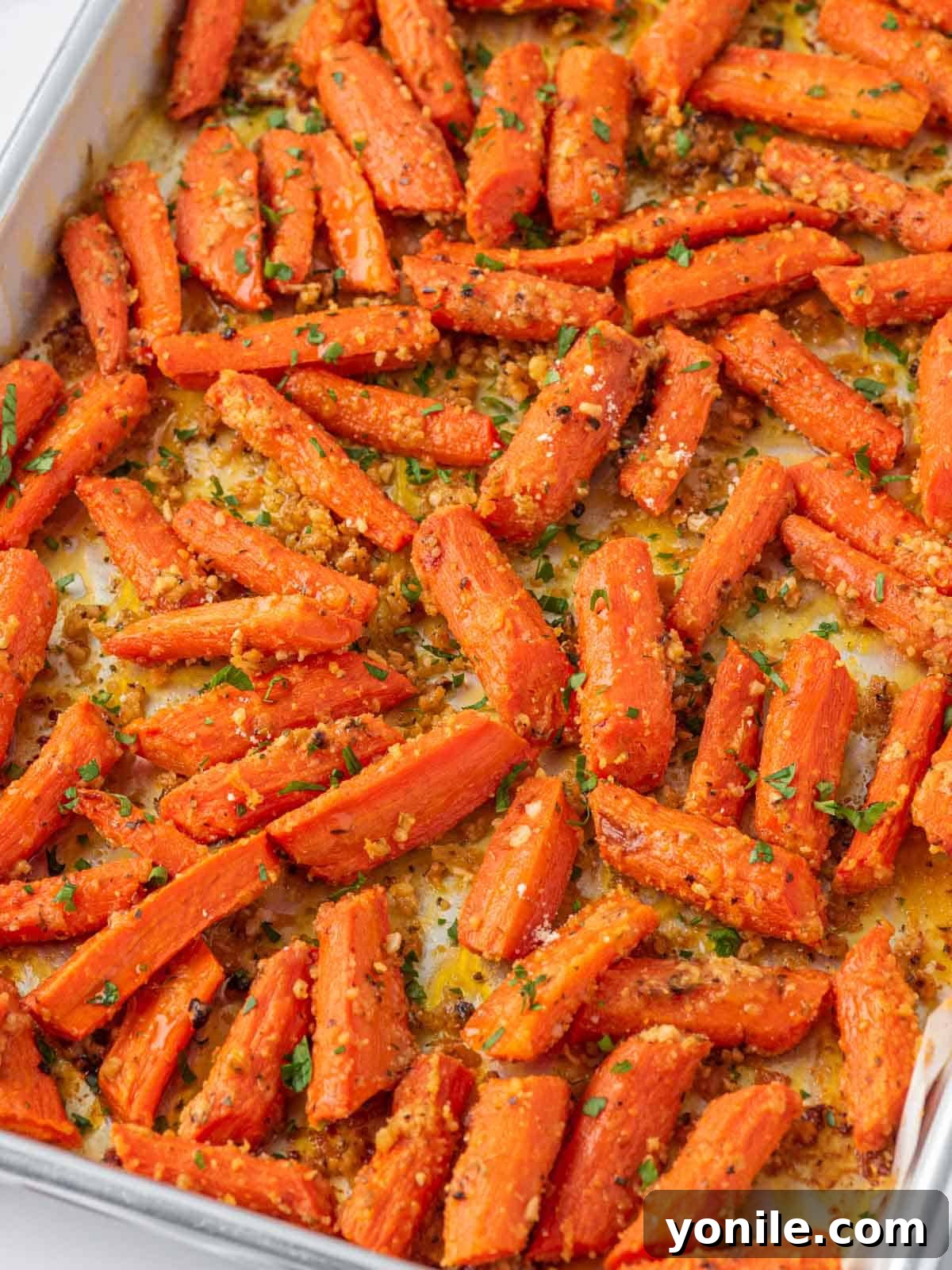 Oven roasted carrots on a baking tray, glistening and golden-brown, ready to be served.