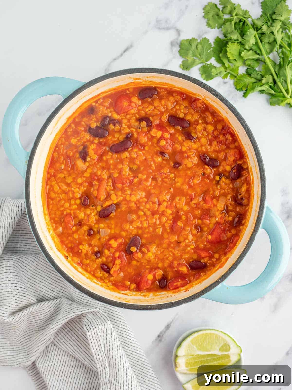 A hearty meatless chili simmers to perfection in a rustic orange Dutch oven, its rich red-brown color and thick texture promising a comforting and flavorful meal, showcasing the completed dish ready for serving.