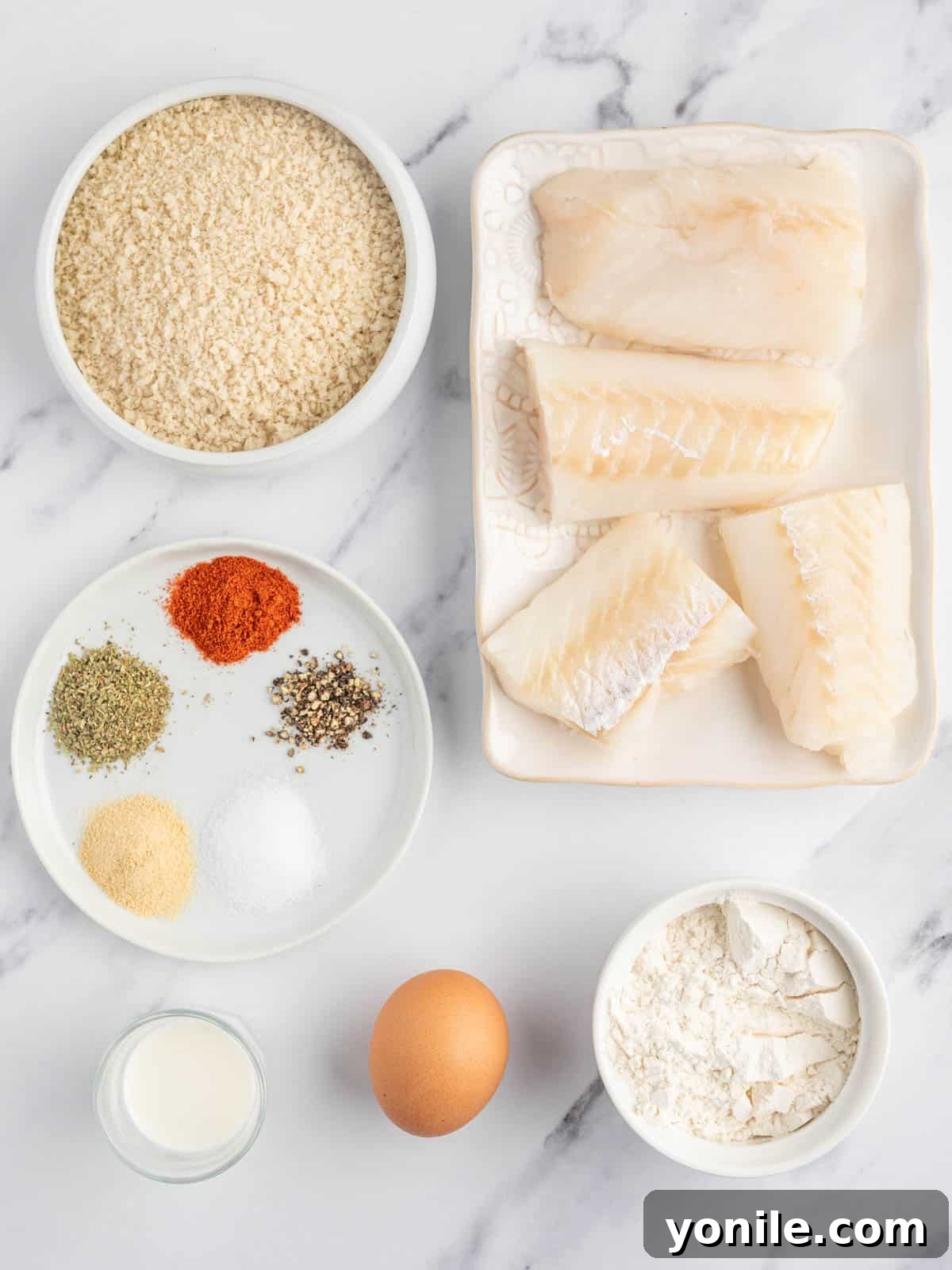 Ingredients for crispy air fryer cod including cod fillets, panko, flour, egg, milk, and spices.