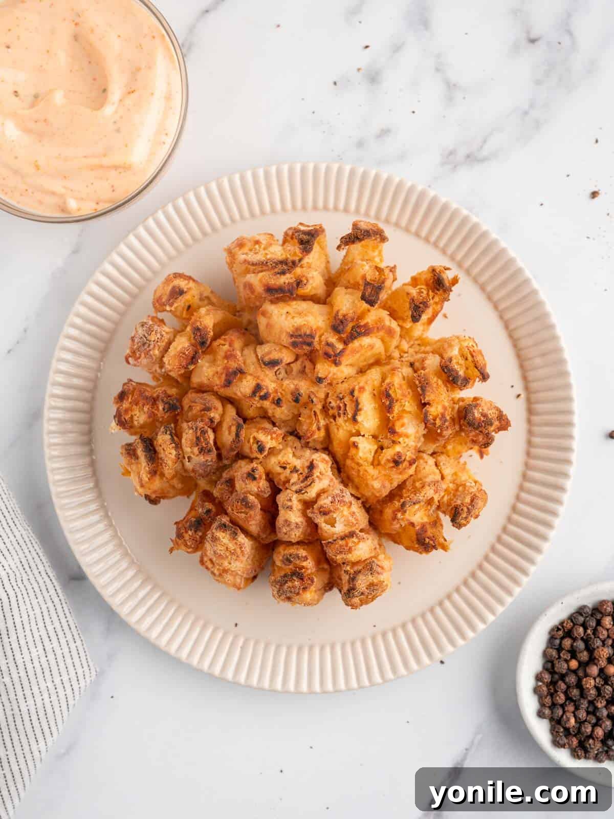 Golden Air Fryer Onion Bloom 2 Crispy Air Fryer Blooming Onion on a serving plate, ready to be enjoyed.