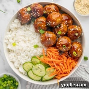 Glazed Teriyaki Chicken Meatballs 9 Teriyaki meatballs on a plate with rice, sliced cucumber and julienned carrots.