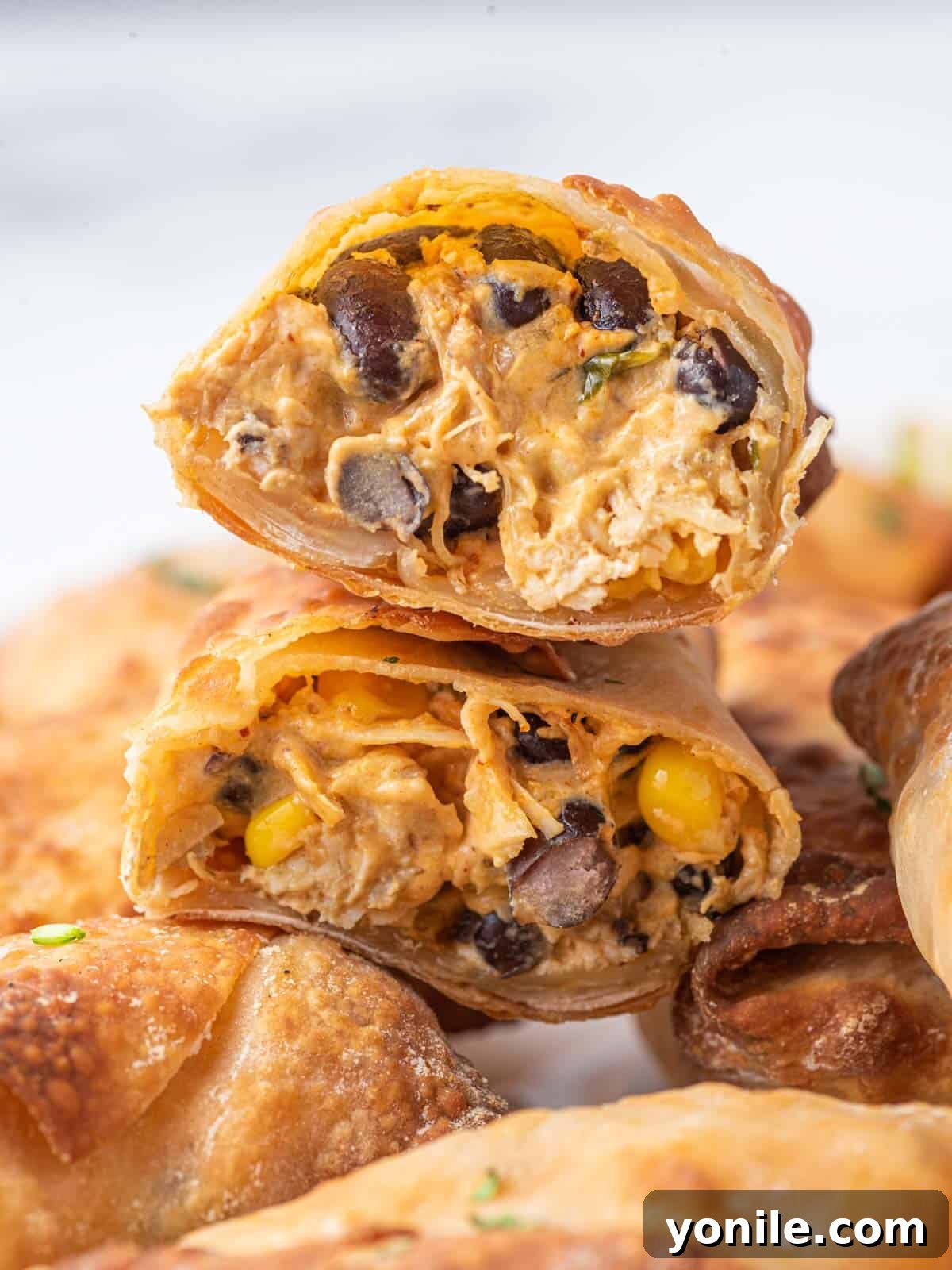A creamy filling oozes out of an air fryer egg roll cut in half, showing its delicious interior.