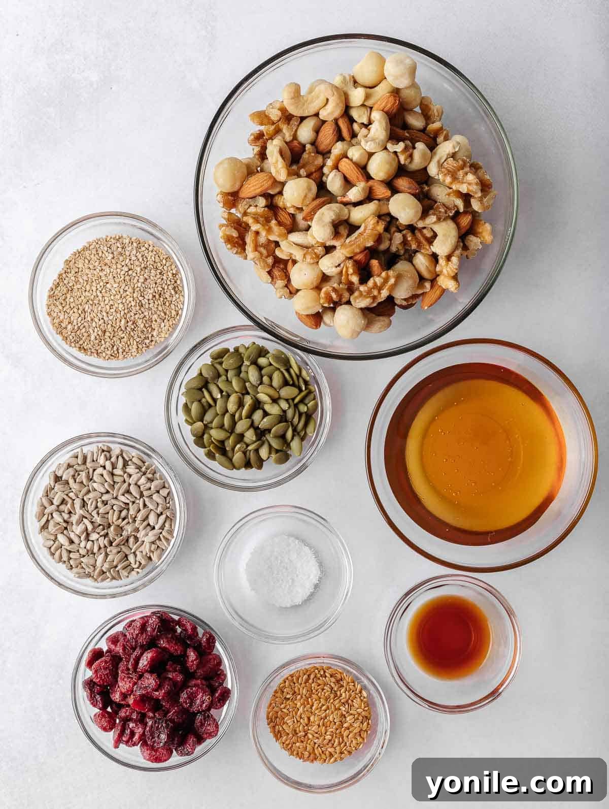 A collection of ingredients spread out, including various nuts, dried cranberries, and seeds, ready for homemade nut bars.