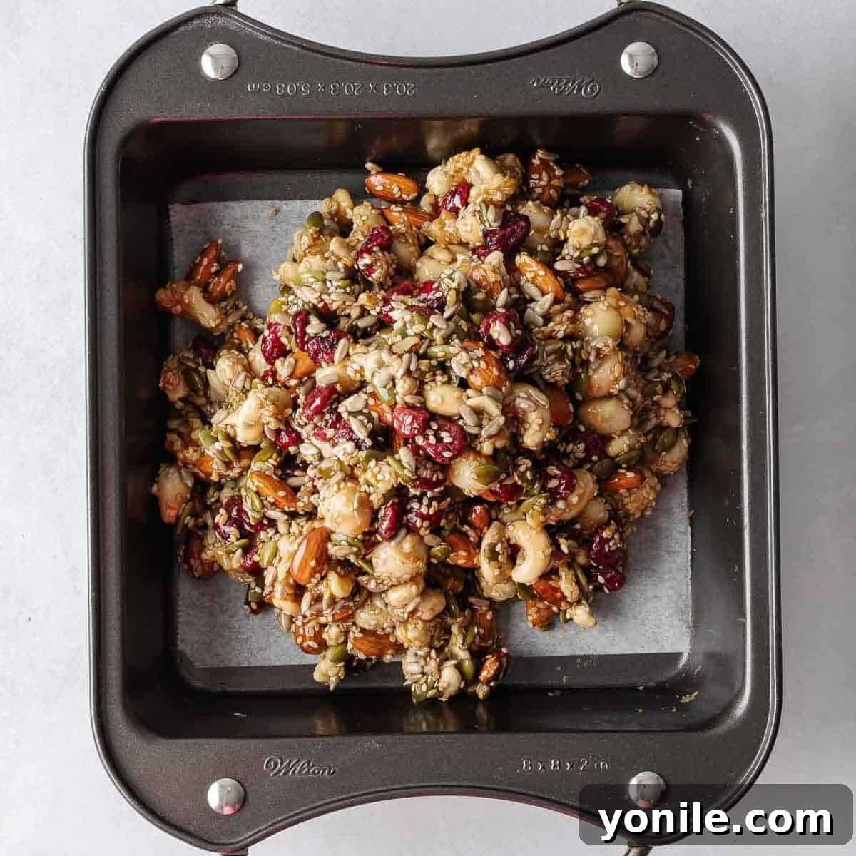 Seed and nut mixture transferred into a parchment-lined baking tray, ready for pressing.