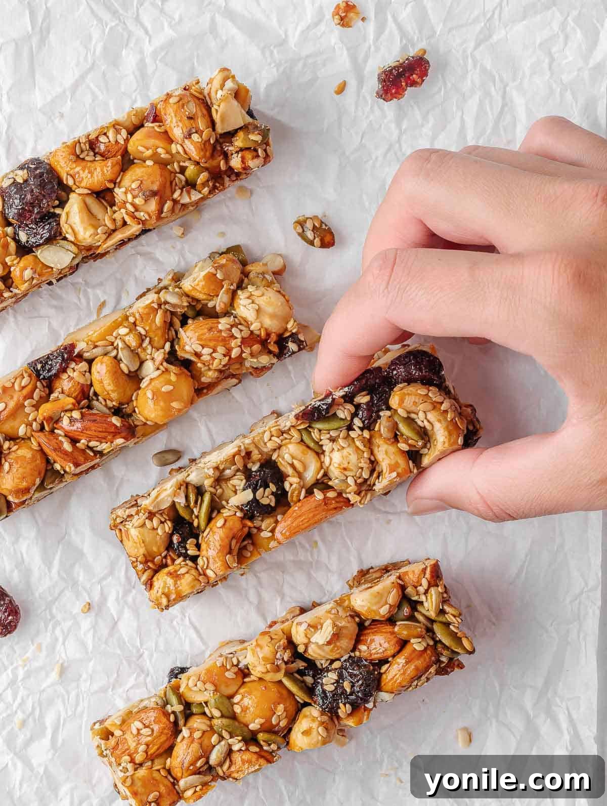 A hand reaching for a healthy nut and seed bar from a stack.