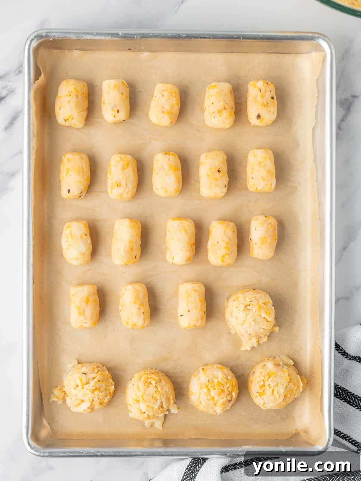 Scoops of potato and cheese mixture are formed into tater tots.