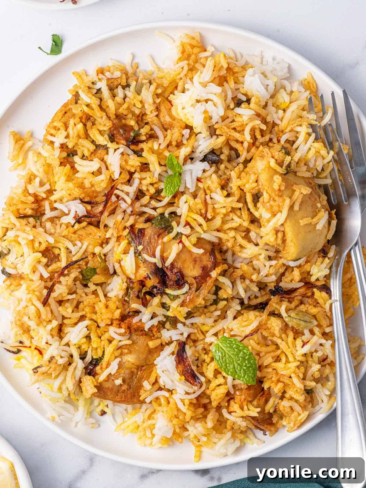 Quick Chicken Biryani 8 Two forks resting on a plate of perfectly cooked homemade chicken biryani, showcasing the fluffy rice and tender chicken.