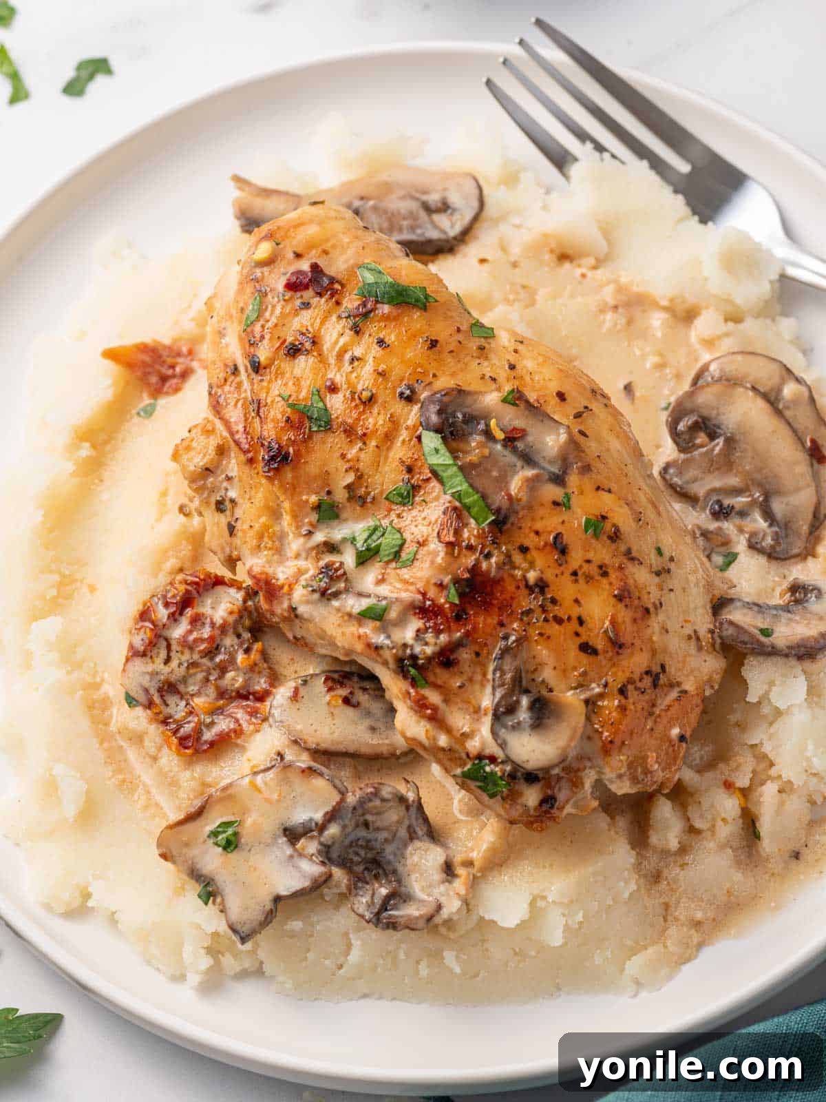A close-up shot of a Stuffed Chicken Marsala breast, with creamy sun-dried tomato and cheese filling gently oozing out, demonstrating its rich texture.