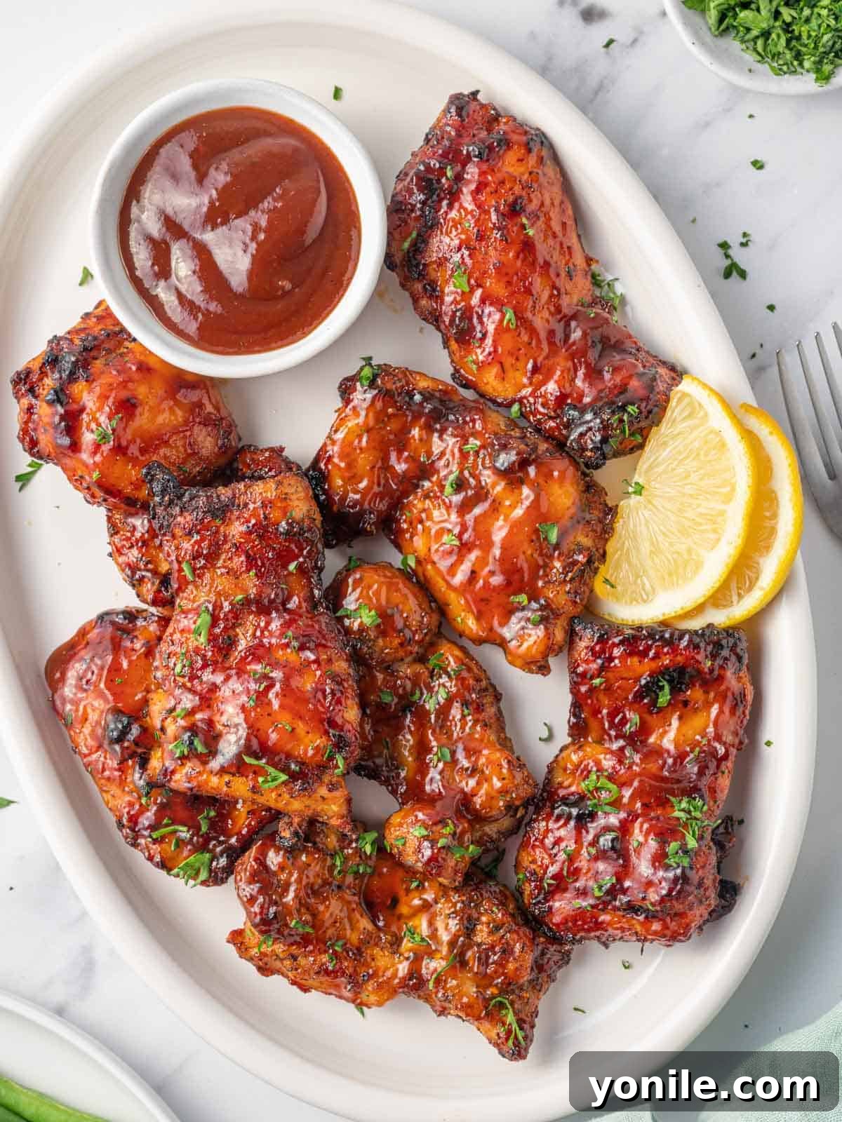 Air Fryer BBQ Chicken Perfection 2 Air fryer bbq chicken on a plate with extra barbecue sauce.