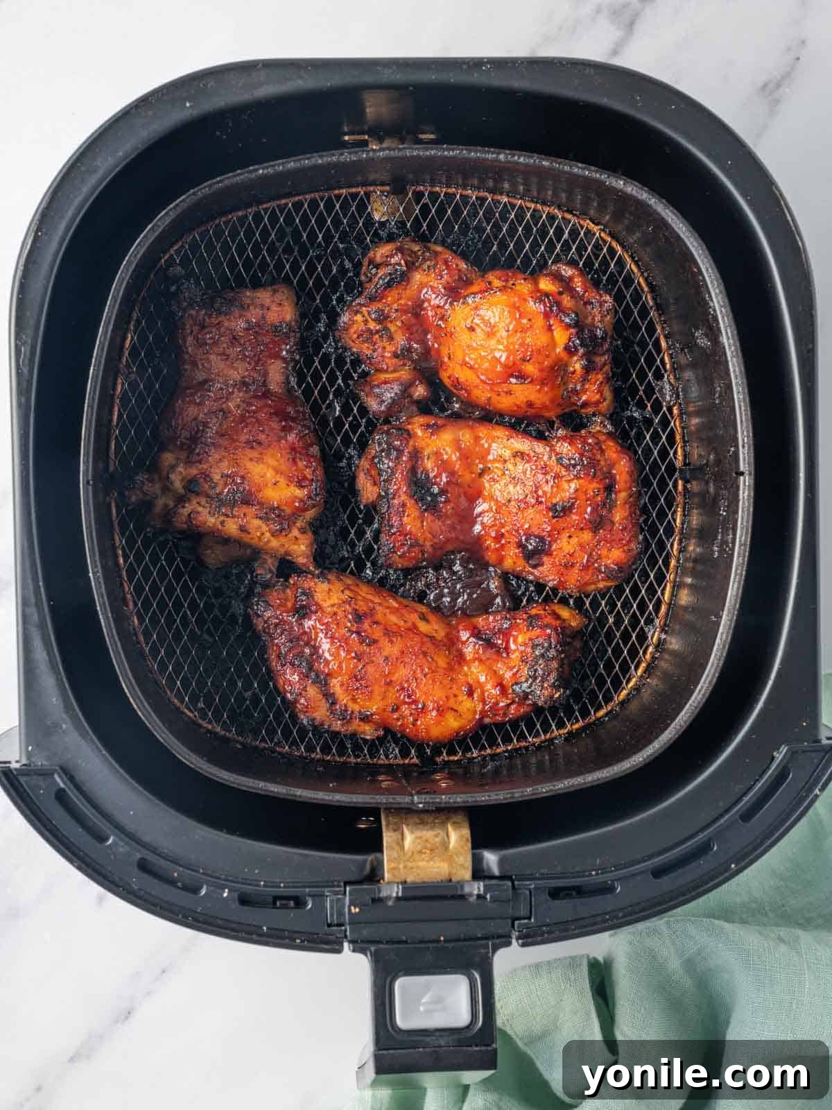 Air Fryer BBQ Chicken Perfection 6 Finished bbq chicken thighs resting in an air fryer basket.
