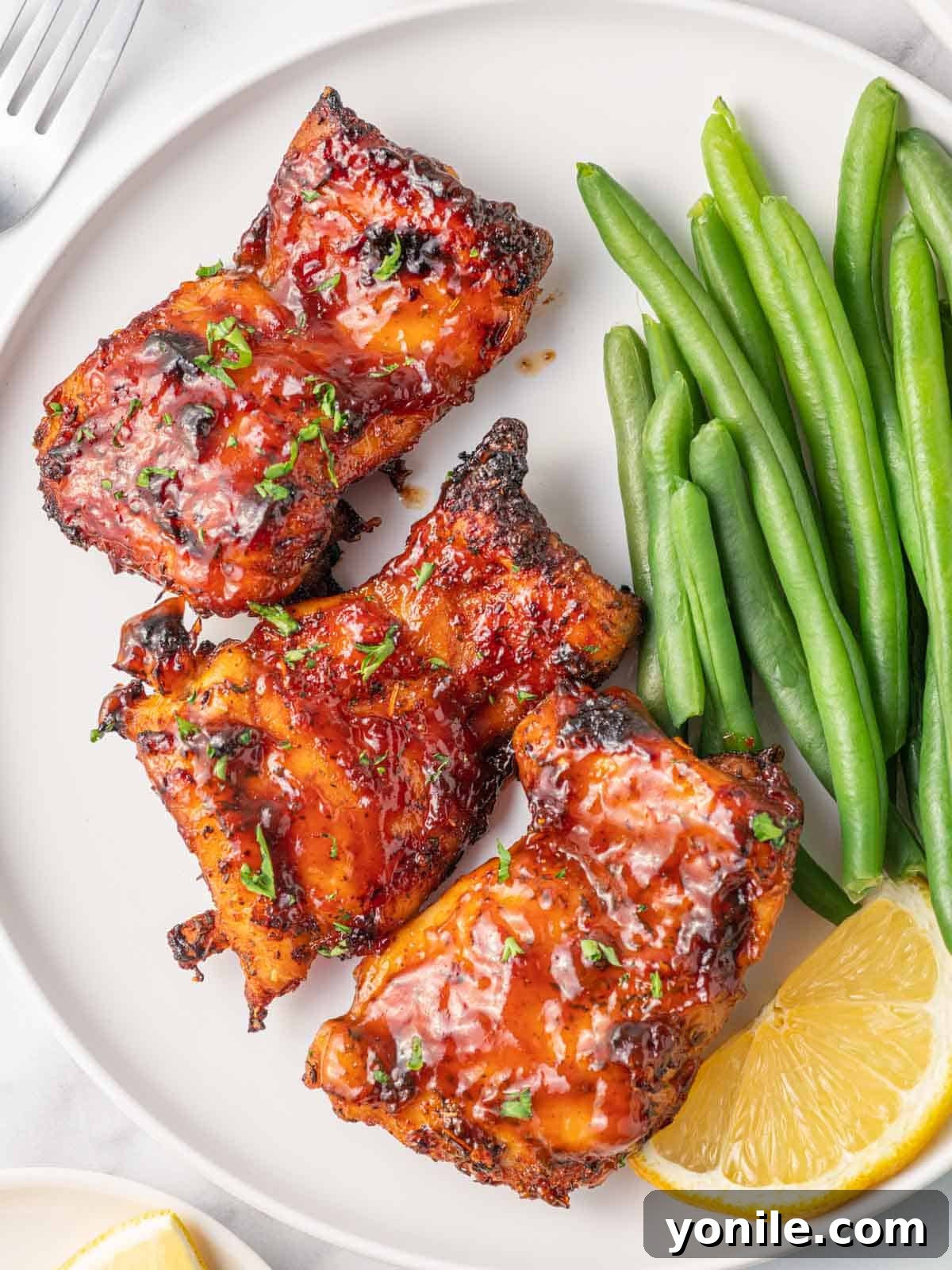 Air Fryer BBQ Chicken Perfection 8 Best air fryer chicken thighs on a plate with green beans.