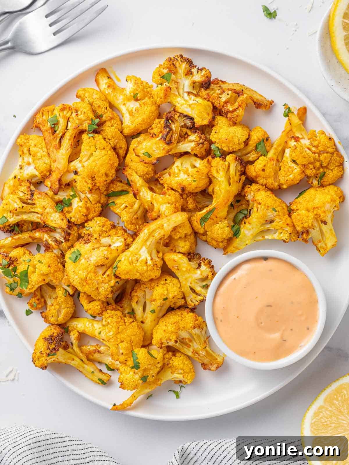 Perfectly roasted air fryer cauliflower bites on a serving tray with a vibrant dipping sauce, ready to be enjoyed.