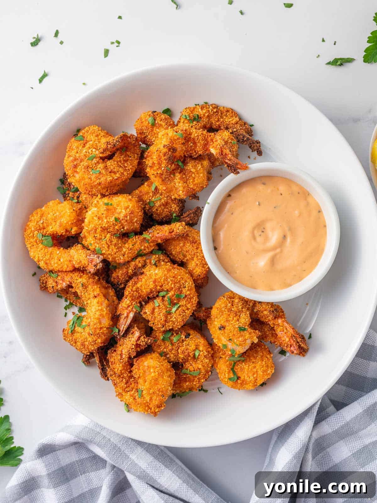 Crispy Air Fryer Keto Shrimp 2 Air fried shrimp coated with almond flour on a plate, garnished with fresh herbs and lemon.