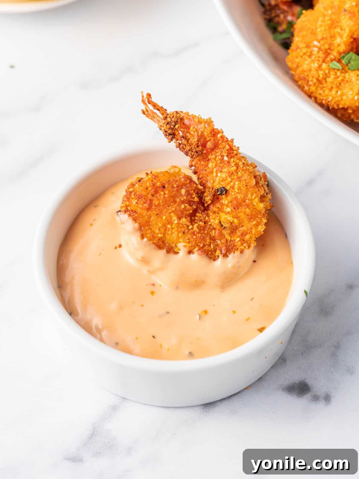 Crispy Air Fryer Keto Shrimp 8 A bowl of dip with a crispy keto breaded shrimp, ready for enjoyment.