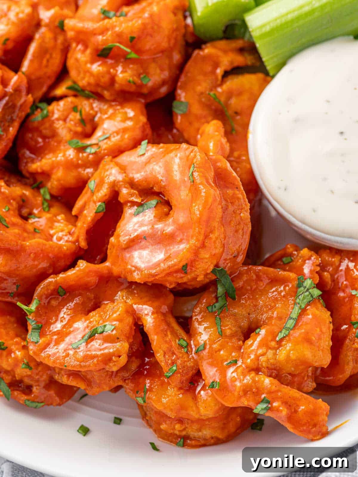 A close-up of perfectly coated spicy fried buffalo shrimp, garnished with fresh parsley and ready to be dipped.
