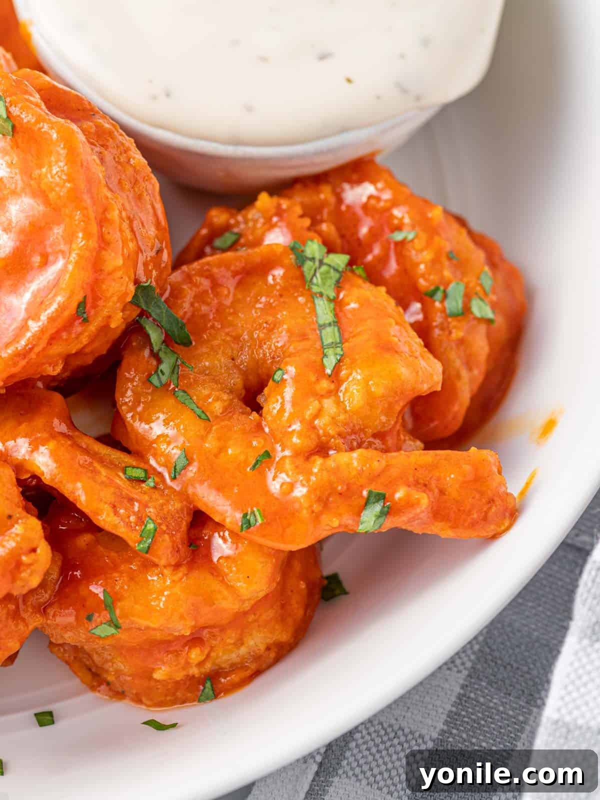 A close-up of perfectly coated spicy fried buffalo shrimp, garnished with fresh parsley and ready to be dipped in ranch or blue cheese dressing.