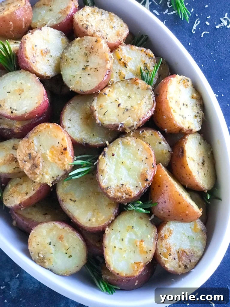 Parmesan roasted potatoes served in an elegant white dish, garnished with fresh herbs, showcasing their crispy texture.