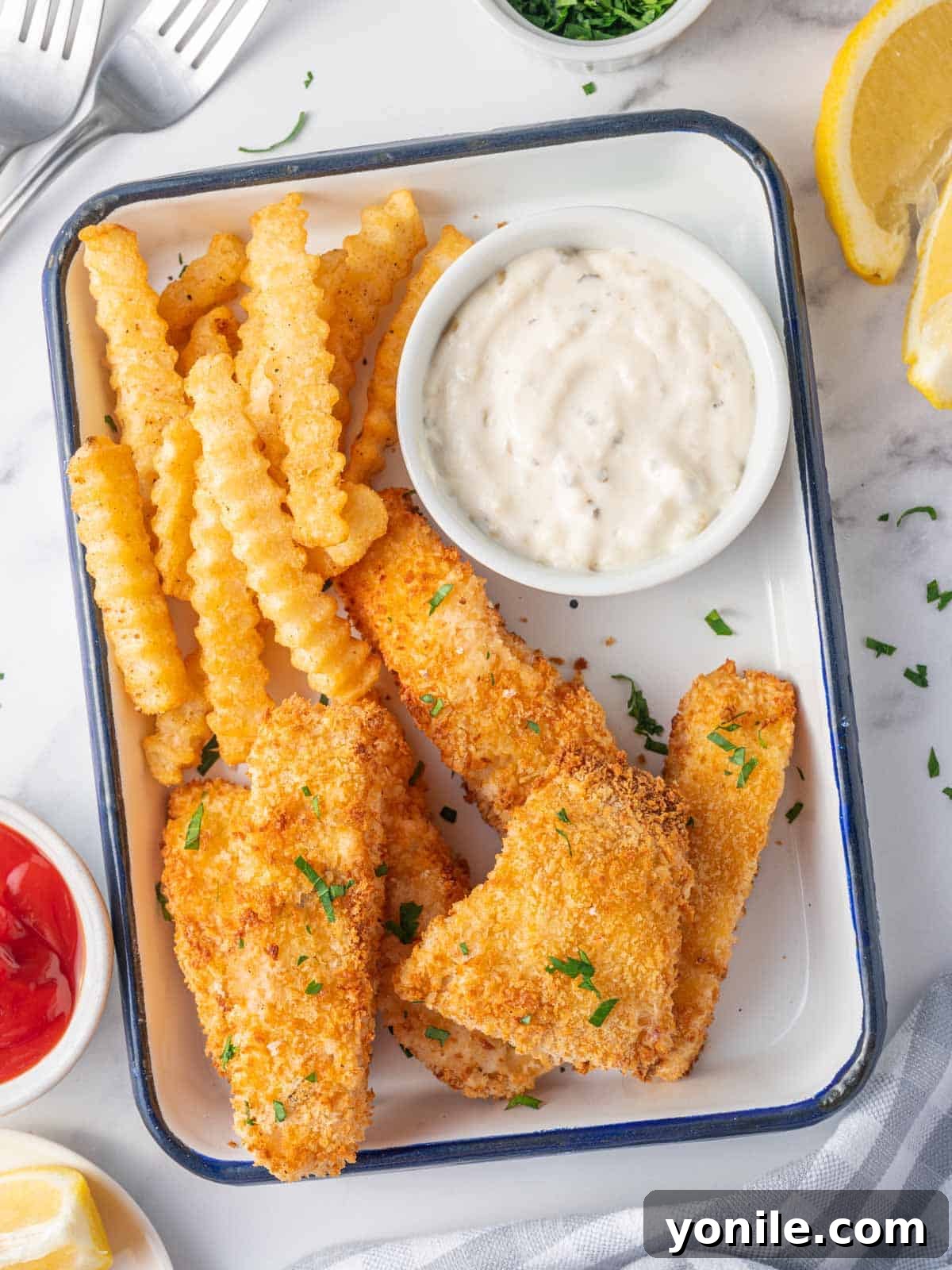 Fish and chips on a plate with tarter sauce.