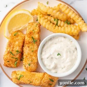 A plate of fish and chips with tarter sauce.