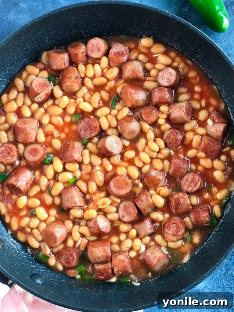 Overhead shot of a bowl of Baked Beans and Sausage Brunch, served with toasted pita bread and a slice of fresh avocado.