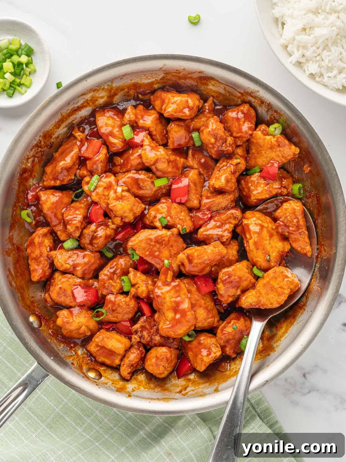 Indo-Chinese Chicken Sensation 2 A spoon lifts a serving of Indo-chinese chicken recipe, showcasing the vibrant sauce and crispy chicken pieces.