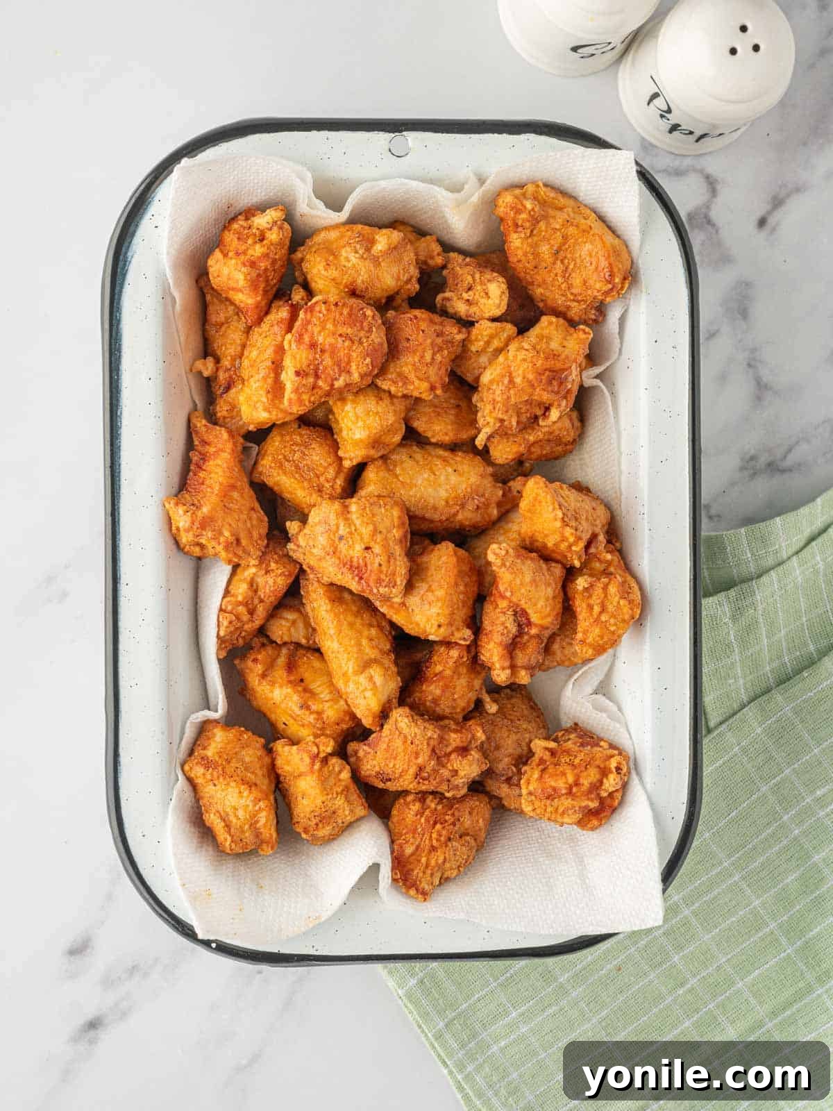 Indo-Chinese Chicken Sensation 5 A tray with deep fried chicken pieces resting on paper towels, golden and crispy.