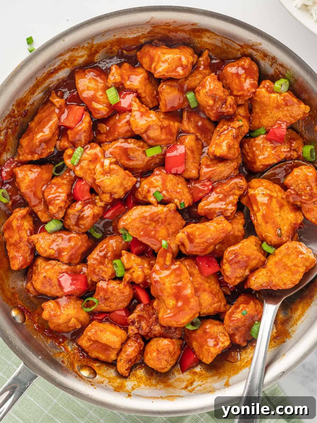 Indo-Chinese Chicken Sensation 7 Chicken with Manchurian sauce being tossed in a skillet, coated evenly.
