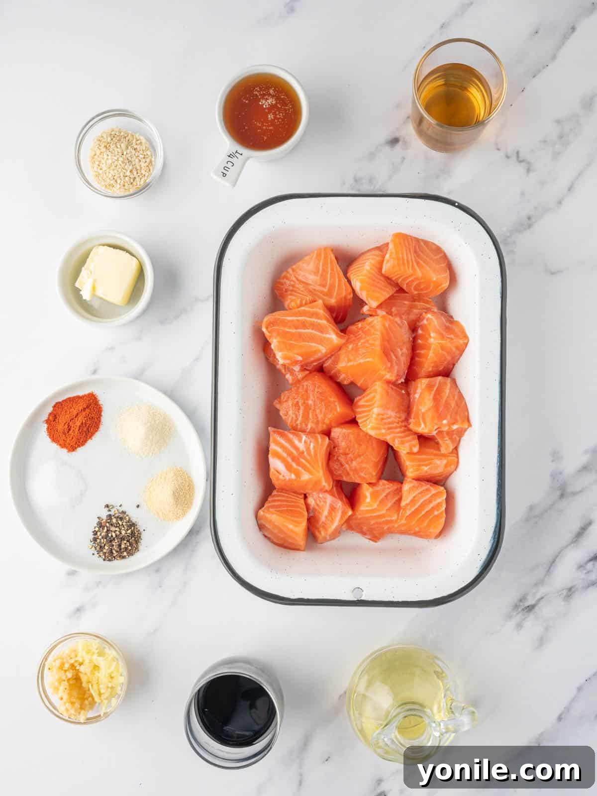 Glazed Honey Garlic Salmon Bites 3 Various fresh ingredients laid out on a wooden surface, including salmon, honey, garlic, ginger, soy sauce, and spices, ready for making honey garlic salmon bites.