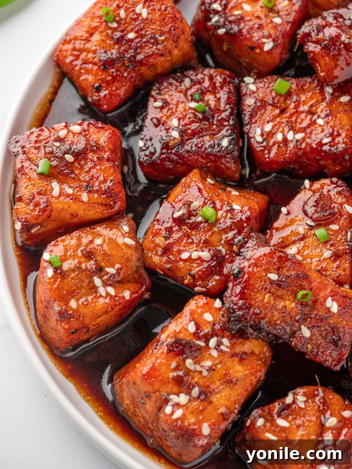 Glazed Honey Garlic Salmon Bites 8 Close-up of perfectly glazed honey garlic salmon bites sprinkled with sesame seeds, showcasing their sticky texture.