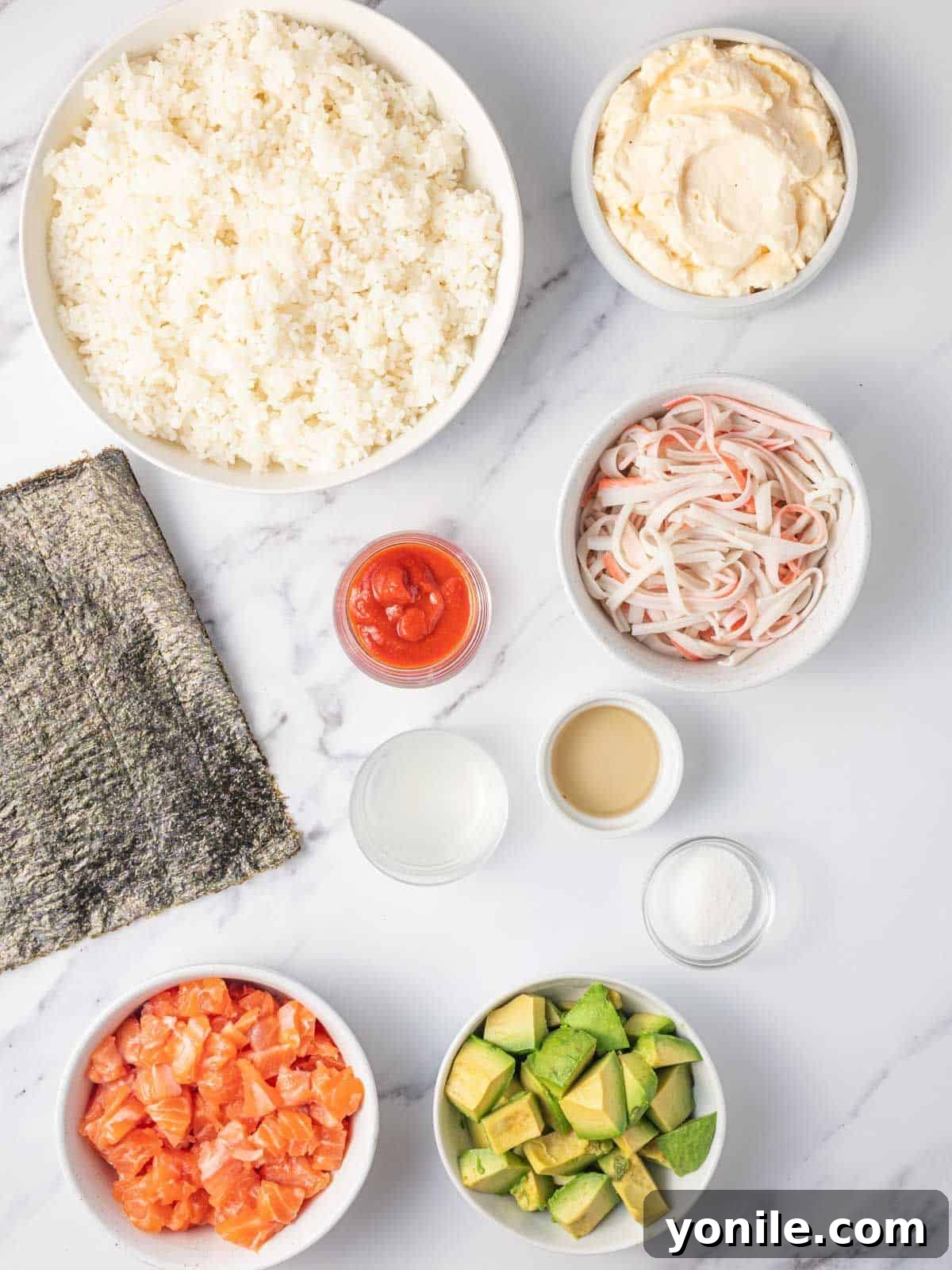 A vibrant selection of fresh ingredients including sushi rice, salmon, imitation crab, avocado, nori, and condiments laid out for sushi burger preparation.