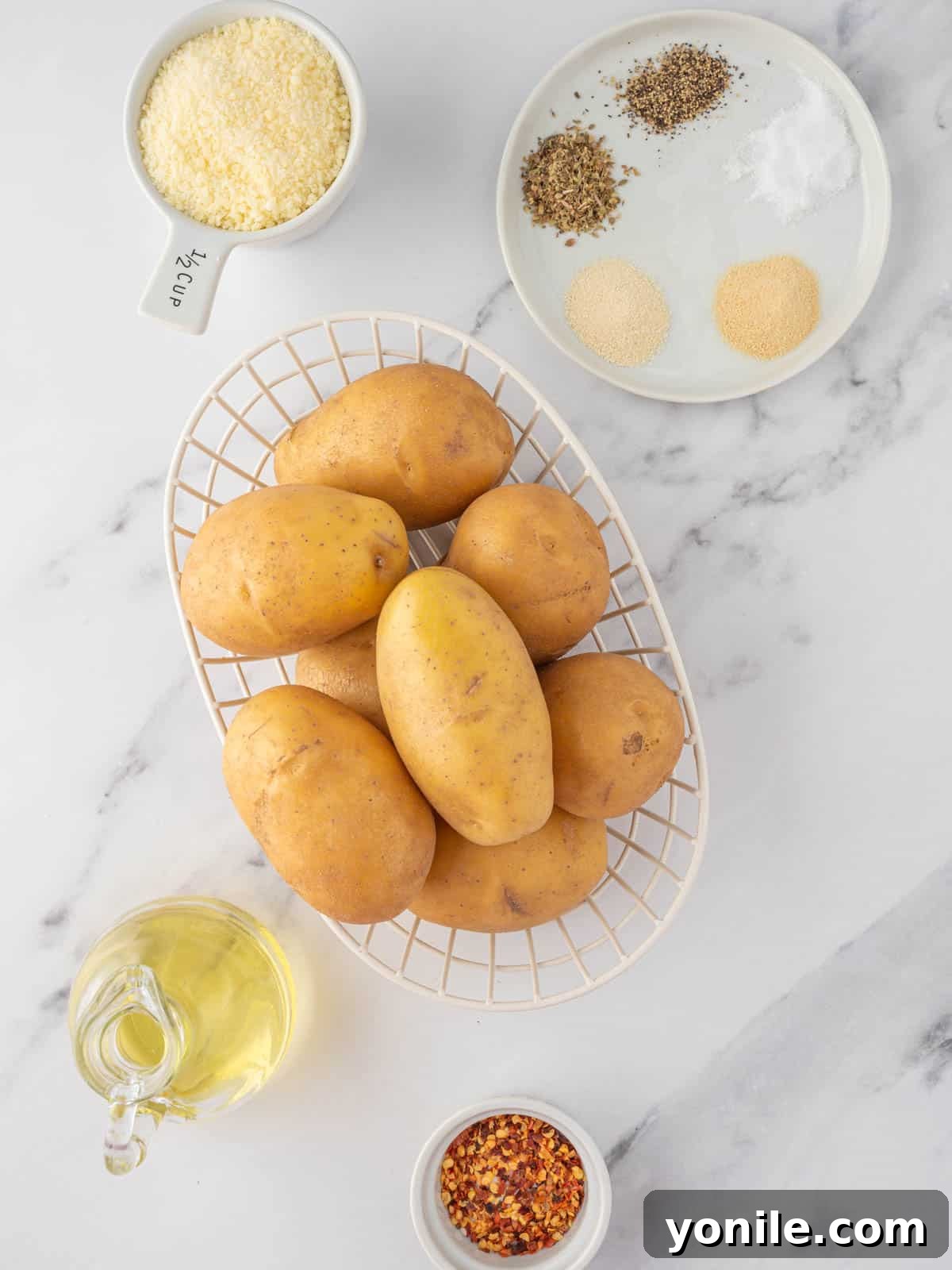 Ingredients needed for tiktok potatoes, including yukon gold potatoes, parmesan cheese, olive oil, and spices.