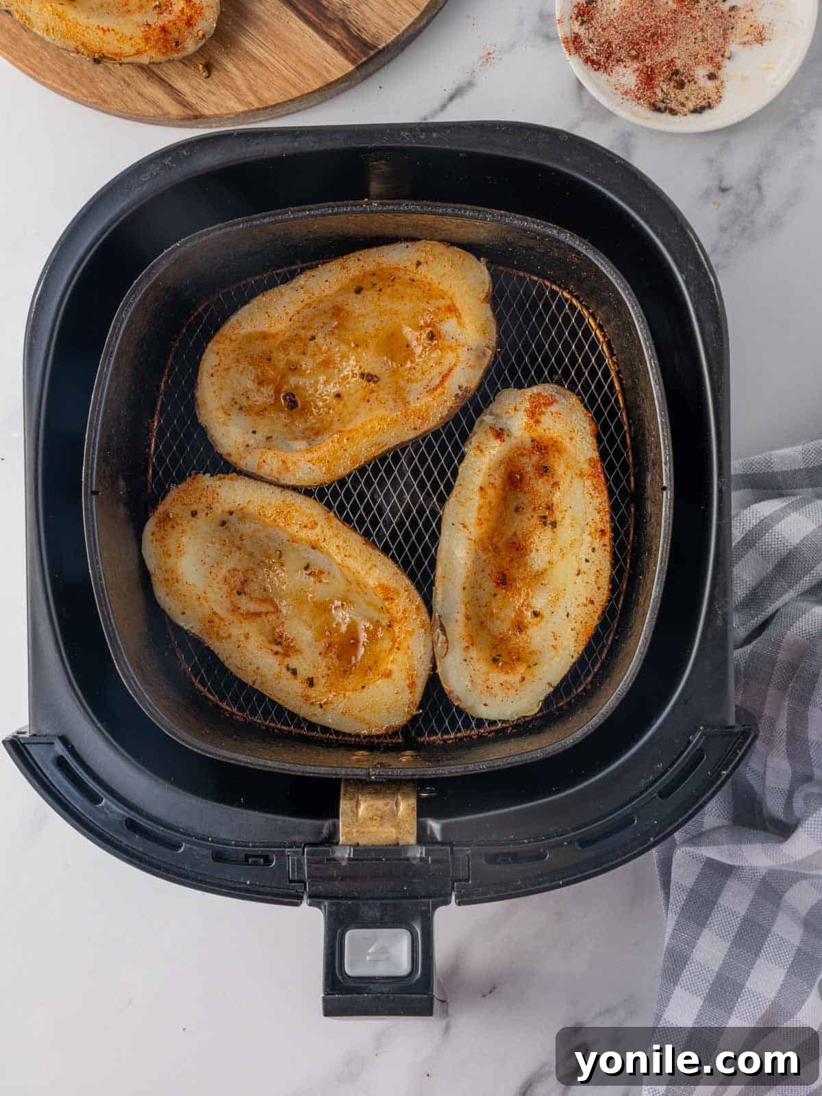 Seasoned potato skins in an air fryer basket.