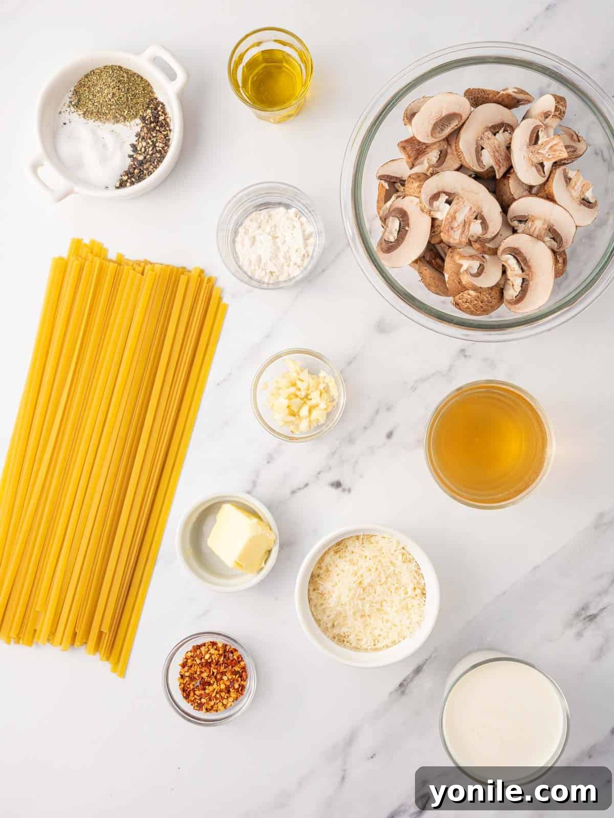 Ingredients needed for creamy mushroom pasta, laid out on a surface.