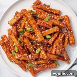 A plate of chilli fries topped with sesame seeds and green onions.