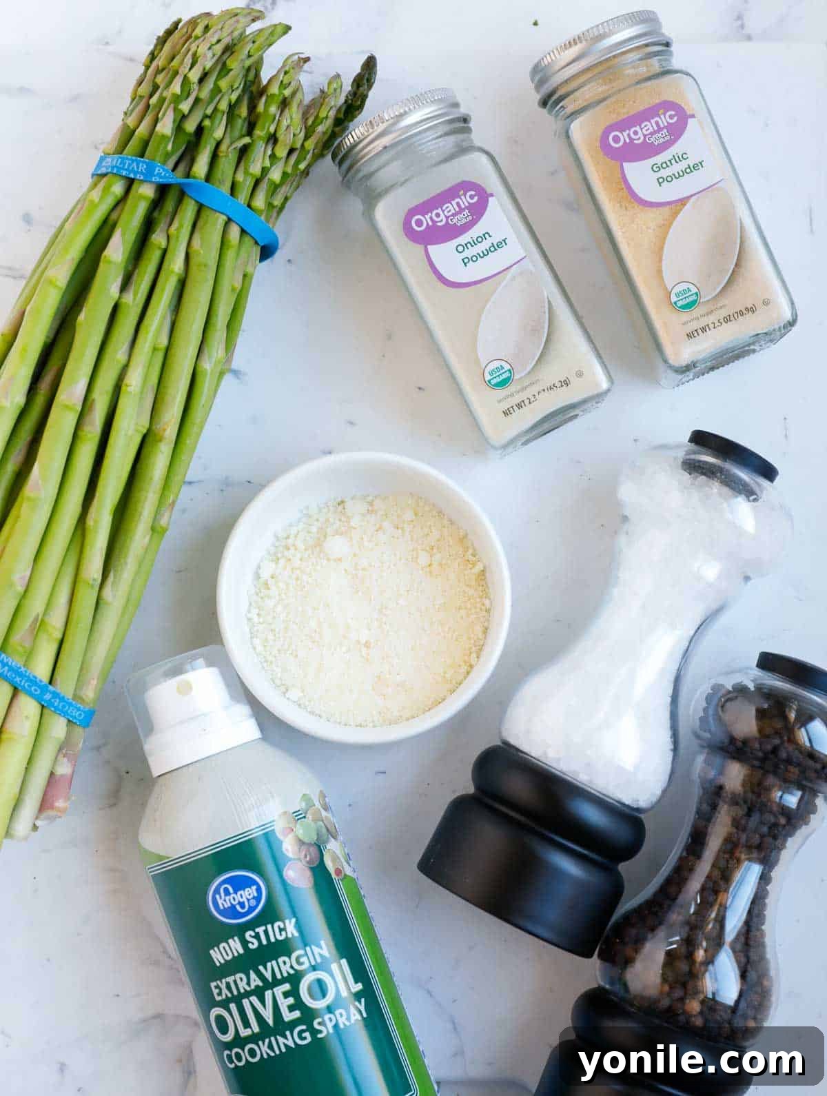Ingredients needed for air fryer parmesan asparagus including fresh asparagus, olive oil spray, parmesan cheese, and various seasonings.