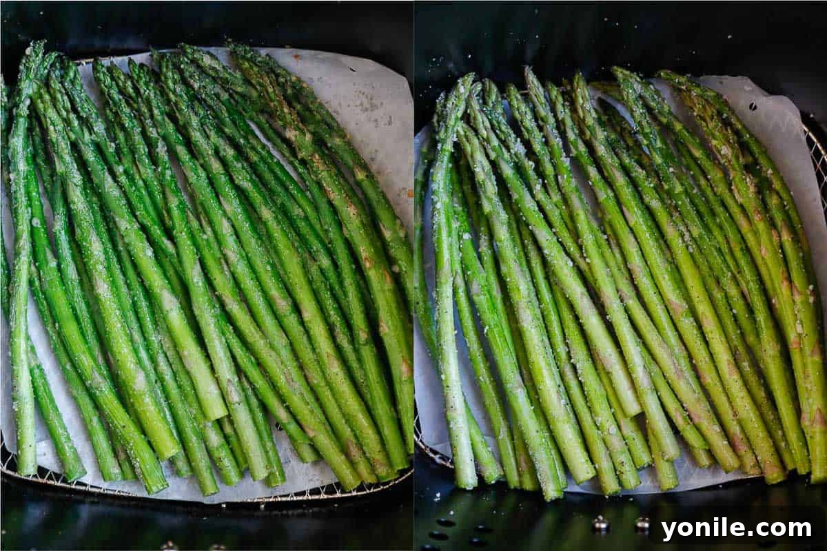 Asparagus cooking in an air fryer basket in a single layer.