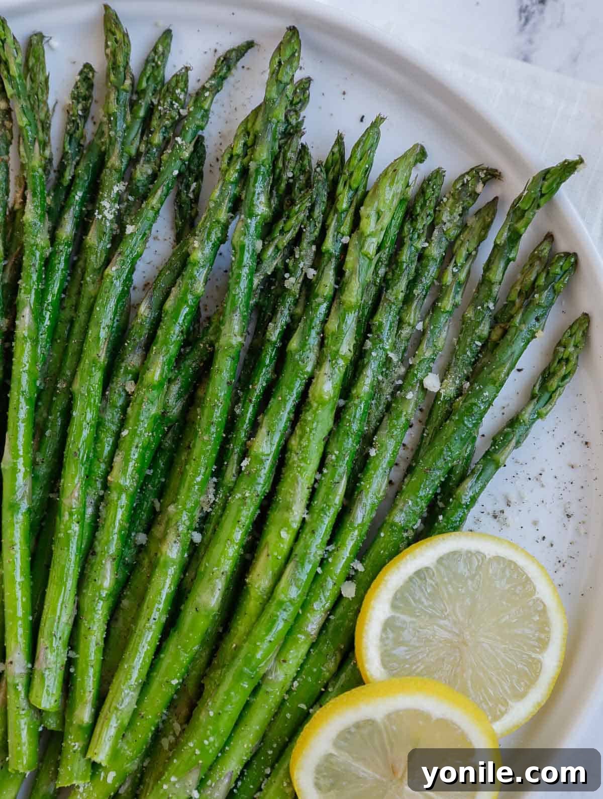 Closeup of air fryer roasted asparagus with melted parmesan cheese.