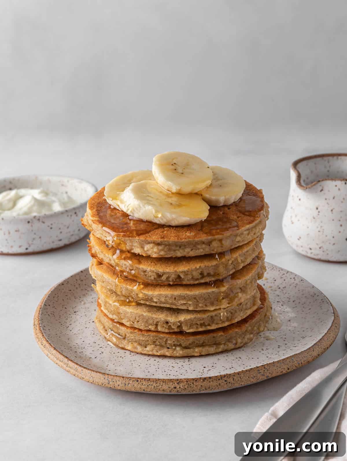 Power-Packed Banana Protein Pancakes 2 A tall stack of golden brown banana protein pancakes, garnished with fresh banana slices and a light dusting of powdered sugar, waiting to be enjoyed as a healthy breakfast.