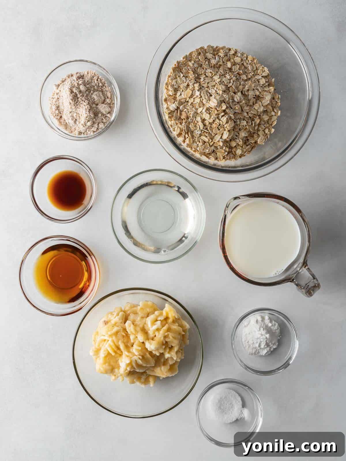 Power-Packed Banana Protein Pancakes 3 A flat lay photograph showcasing all the fresh ingredients for banana protein pancakes, including oats, vanilla protein powder, ripe bananas, coconut milk, and maple syrup.