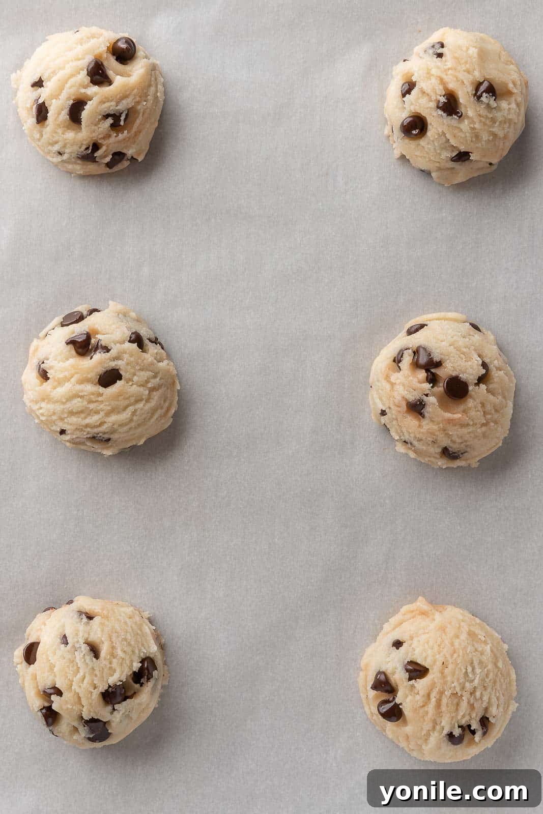 Scoops of egg free cookie dough on parchment paper.