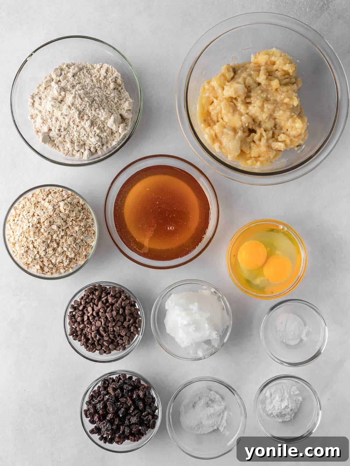 Wholesome Oat Banana Loaf 3 A spread of ingredients laid out on a table, including oats, flour, bananas, eggs, and honey, for healthy oatmeal banana bread.