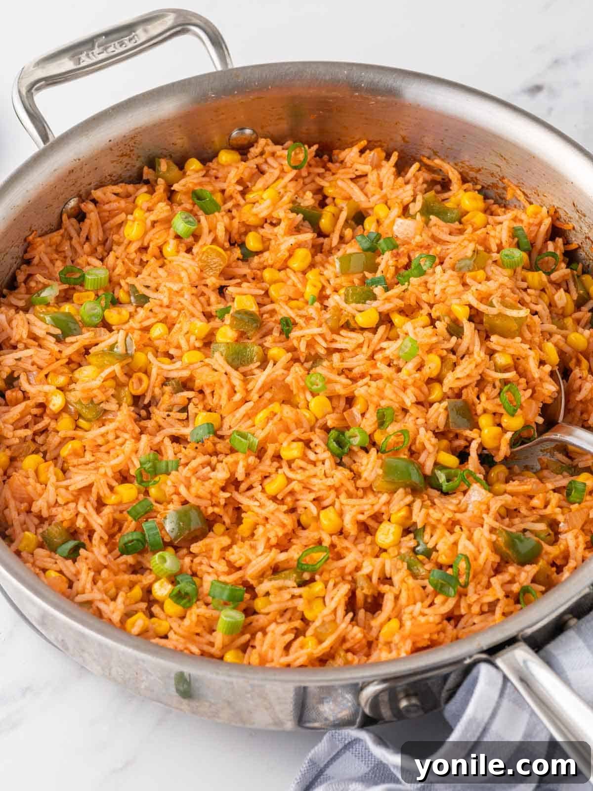 Fiesta Fried Rice 6 A spoon scoops fried Mexican rice from a skillet, showcasing its vibrant colors and fluffy texture.